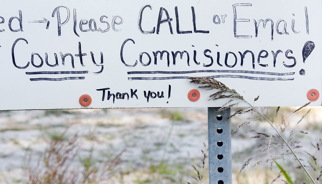A sign asks citizens to call the commissioners